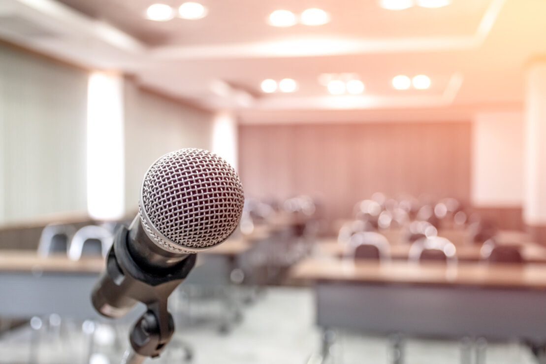 Emcee speaking into a microphone on stage at a corporate event